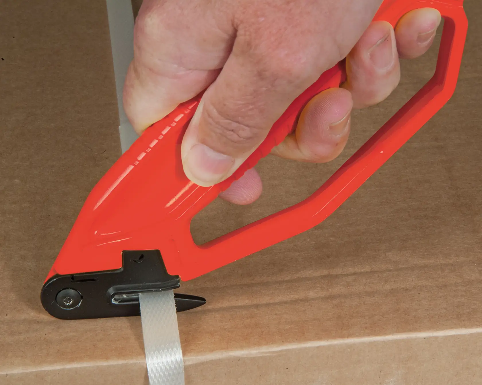 STANLEY 0-10-244 safety cutter in red, photo of tool cutting packaging strap on cardboard box.