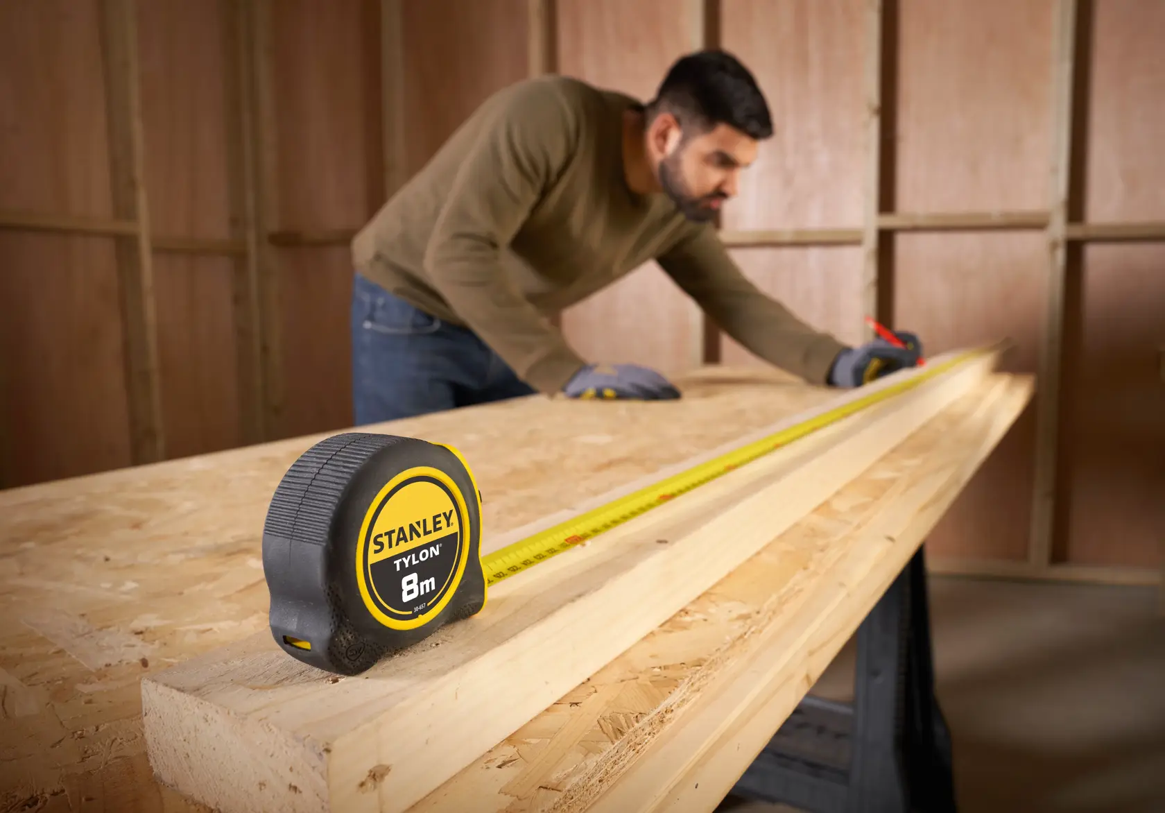 STANLEY 0-30-657 tape measure on wooden workbench, extended for measuring, indoor workspace.