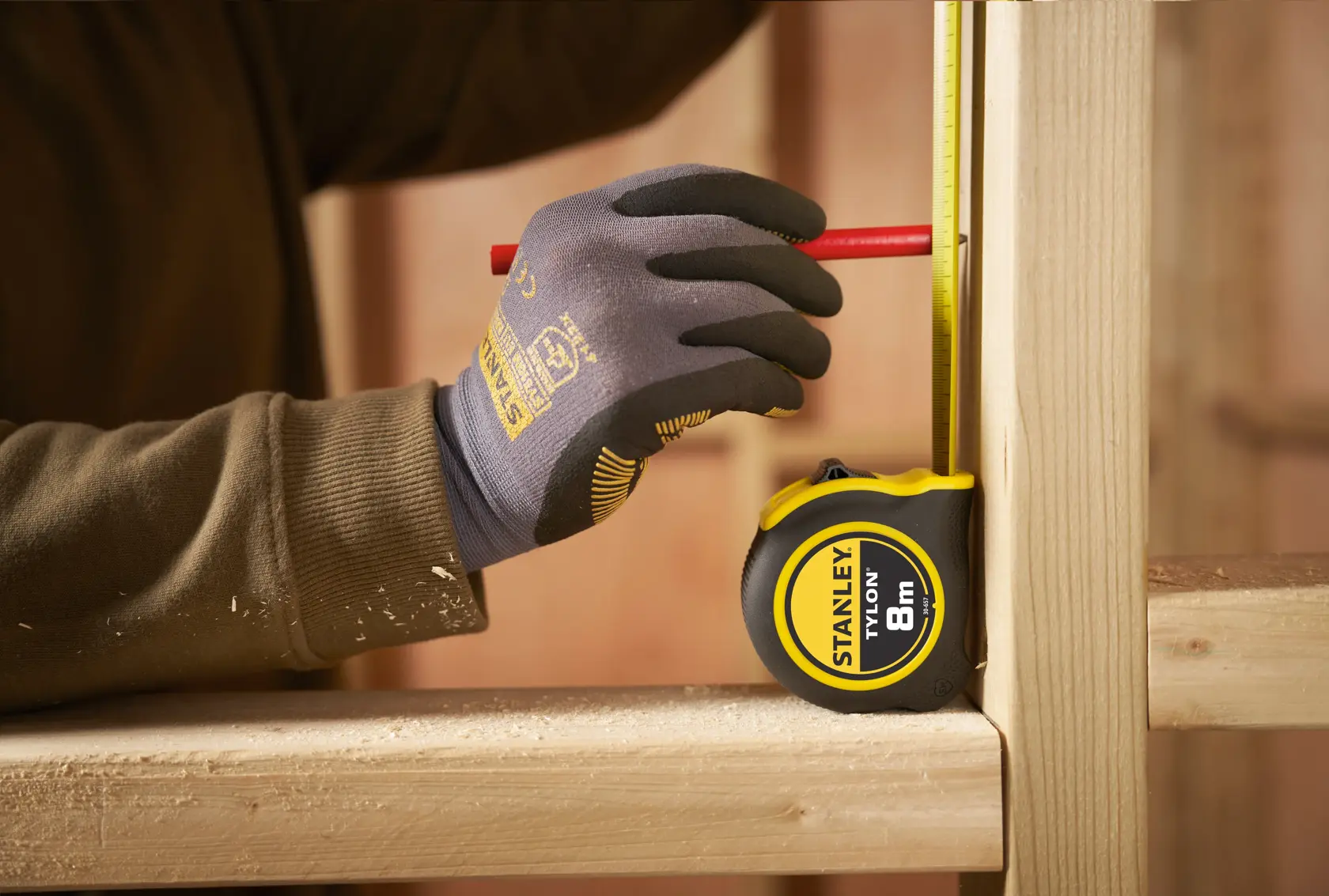 Photo of STANLEY 0-30-657 tape measure, yellow and black, being used to mark wood in construction.