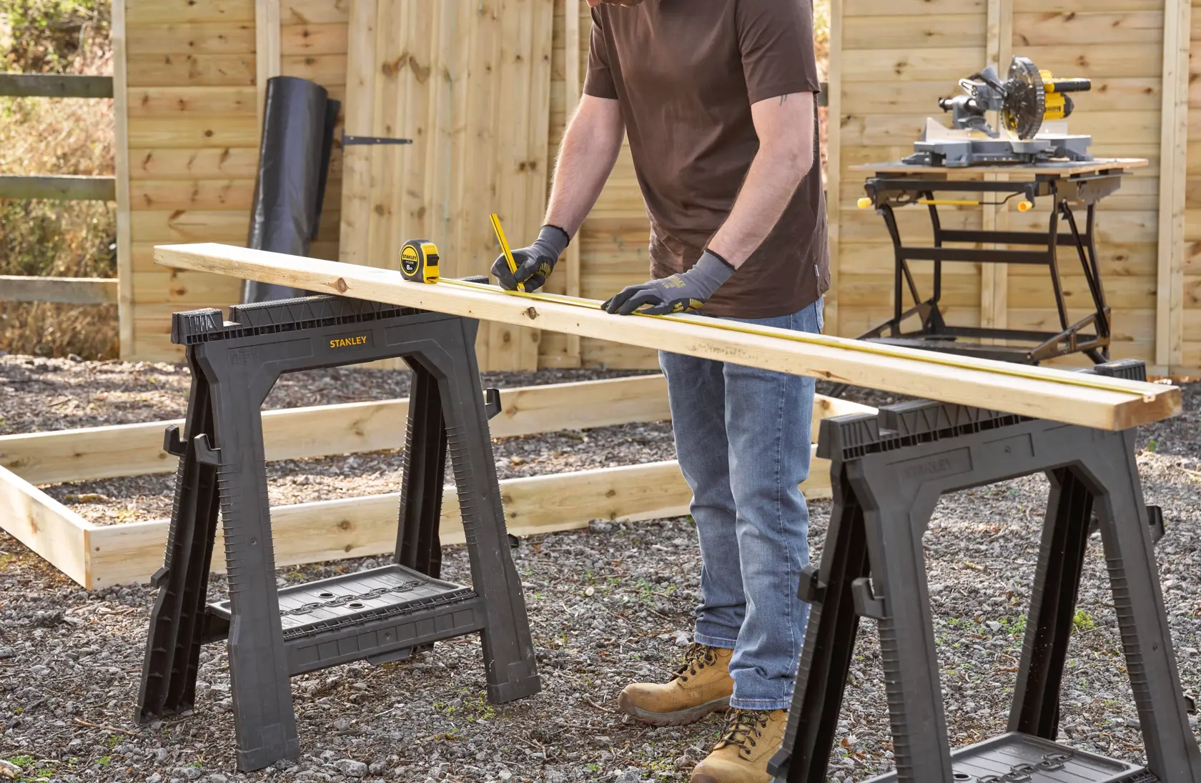 Photo of STANLEY 0-30-657 plastic sawhorses used outdoors for measuring wood in a construction setting.