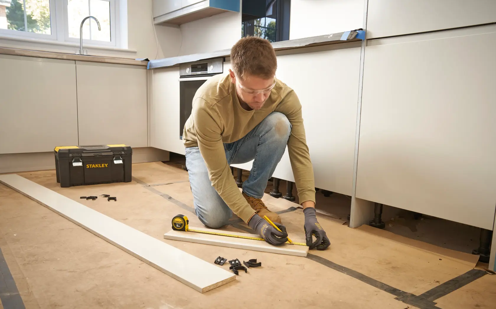Stanley 0-30-697 tape measure and toolbox in kitchen workspace with user measuring wooden plank.