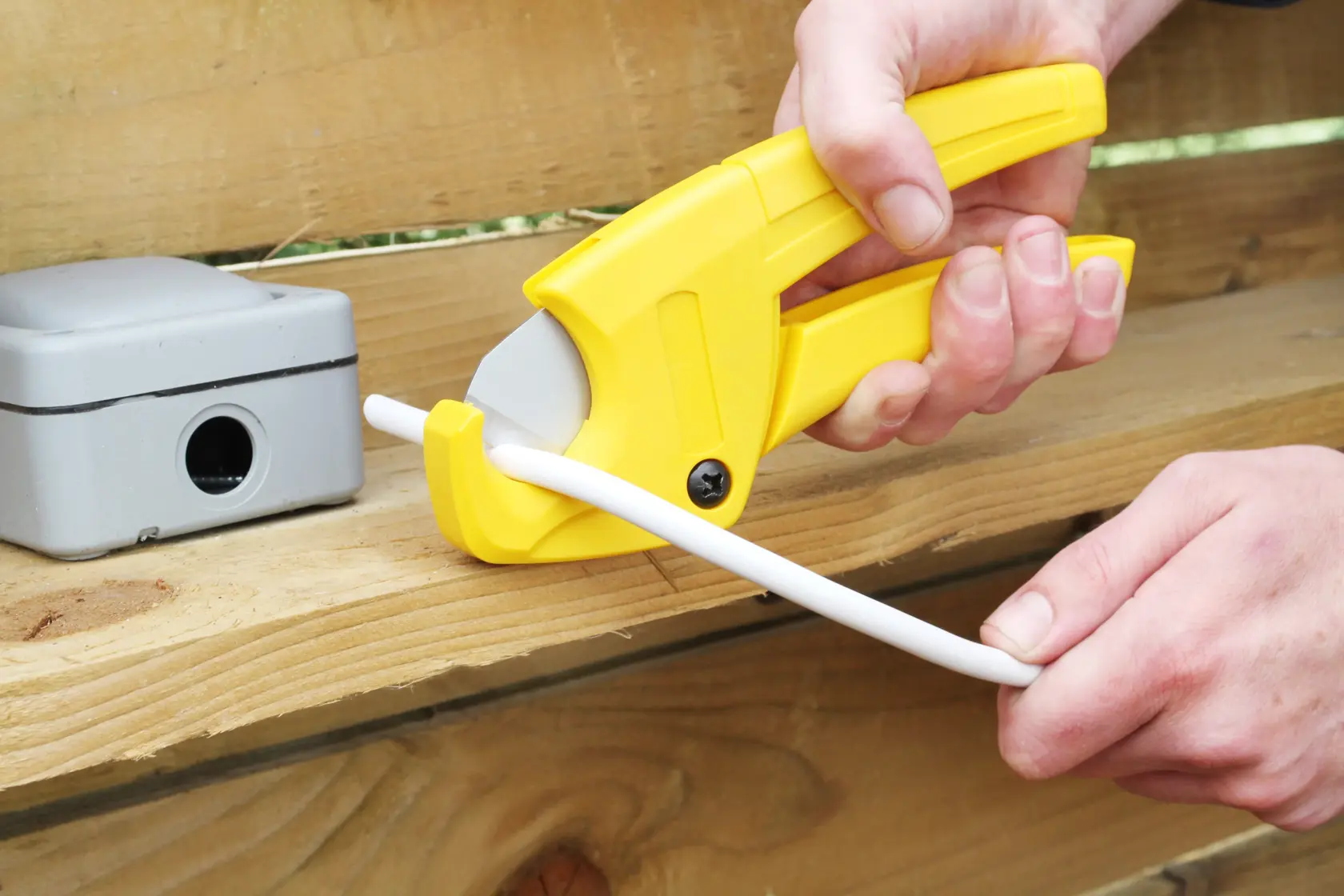 STANLEY 0-70-450 pipe cutter cutting white plastic pipe, handheld, close-up photo.
