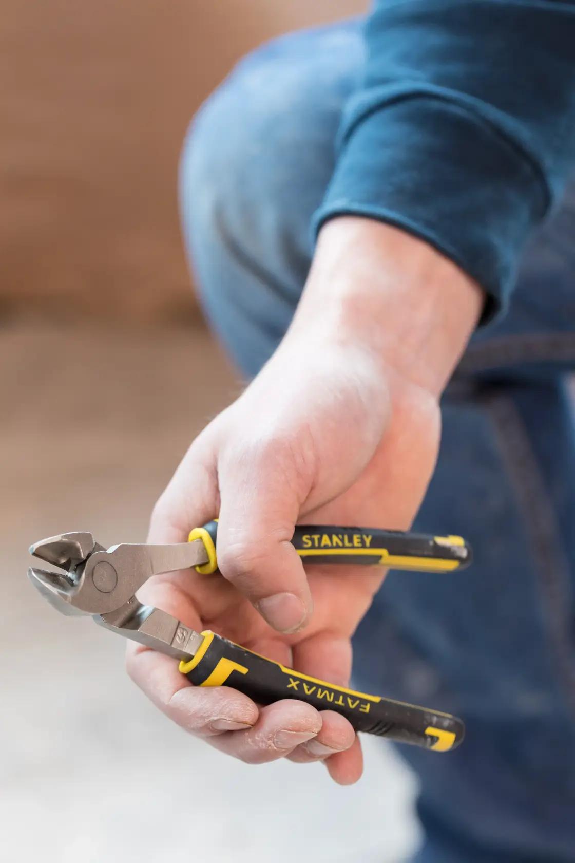 STANLEY 0-89-860 diagonal cutting pliers with black and yellow handles held in hand, close-up photo.