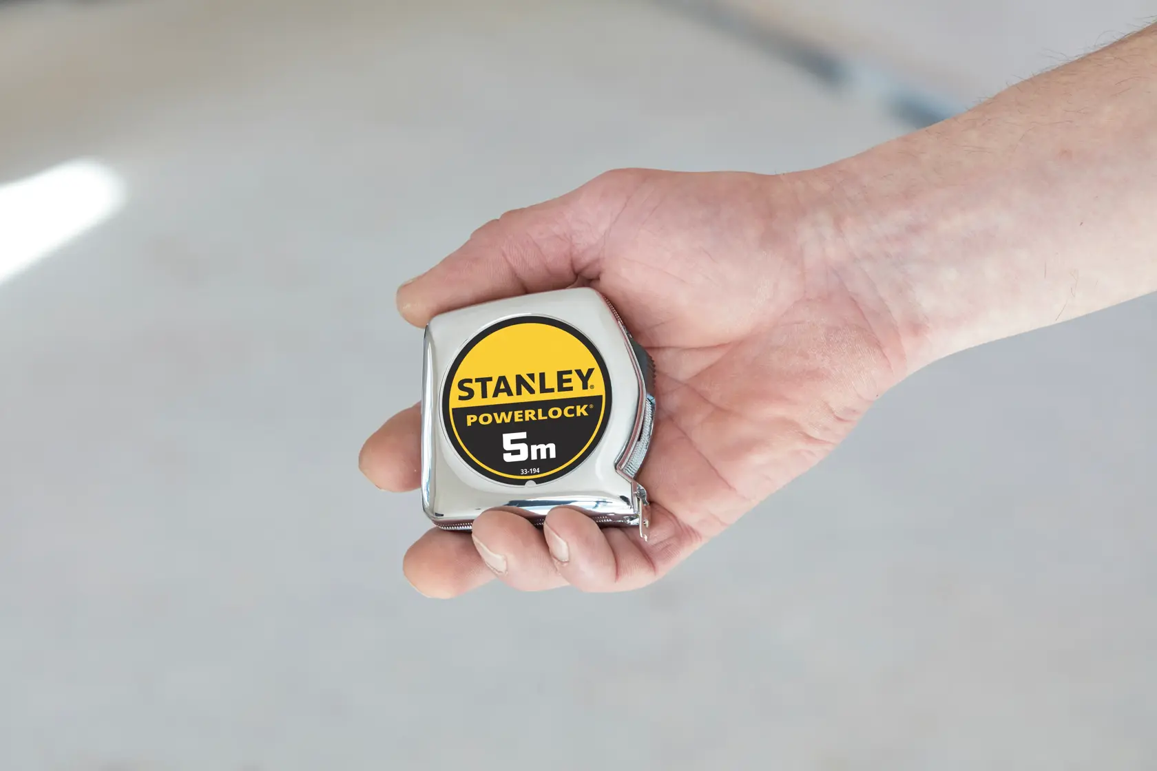 STANLEY 1-33-194 tape measure, PowerLock 5m, held in a hand, close-up view.