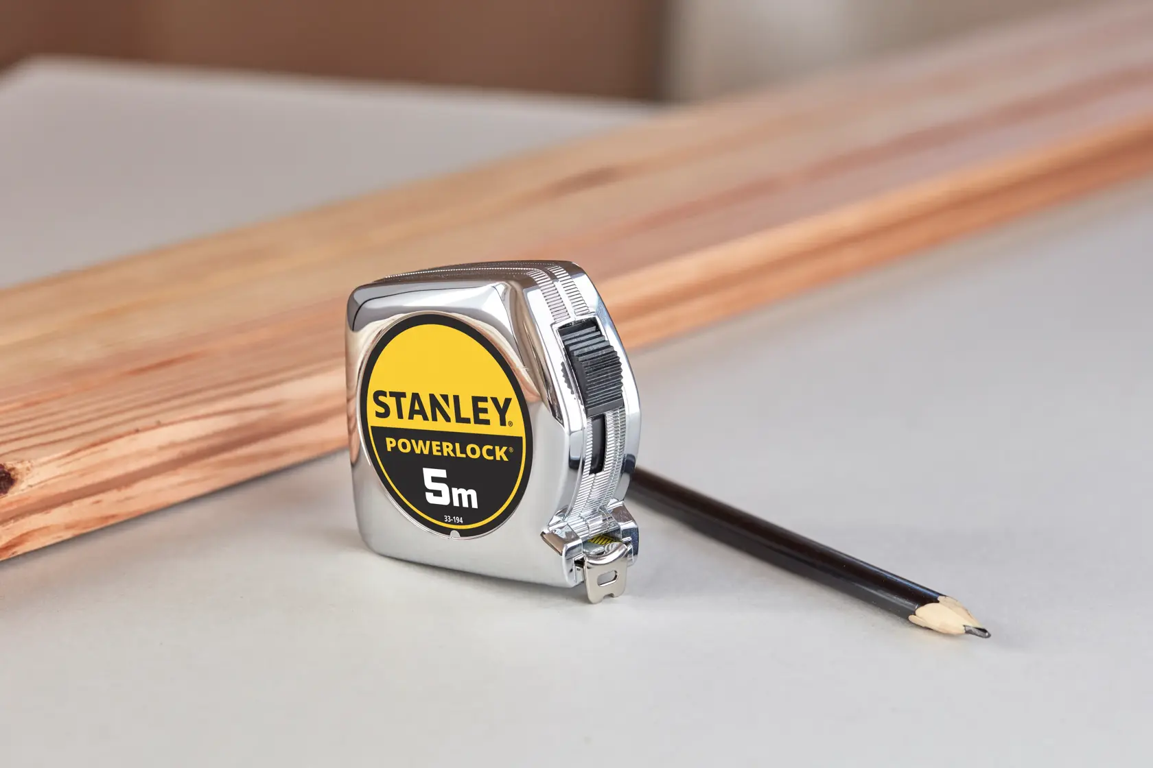 STANLEY 1-33-194 tape measure, PowerLock 5m, photography with pencil and wood in background.