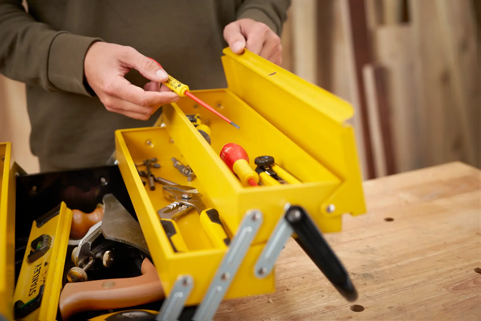STANLEY 1-94-738 yellow metal toolbox with assorted hand tools, photo from above on a workbench.