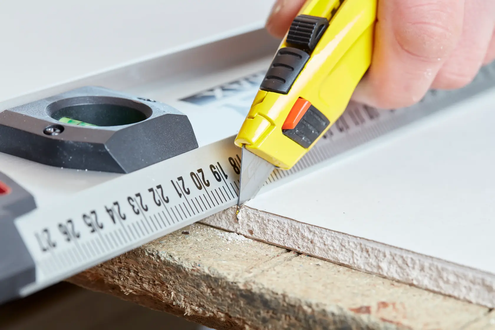 Photo of STANLEY 2-11-800 utility knife cutting drywall along a metal ruler close-up.