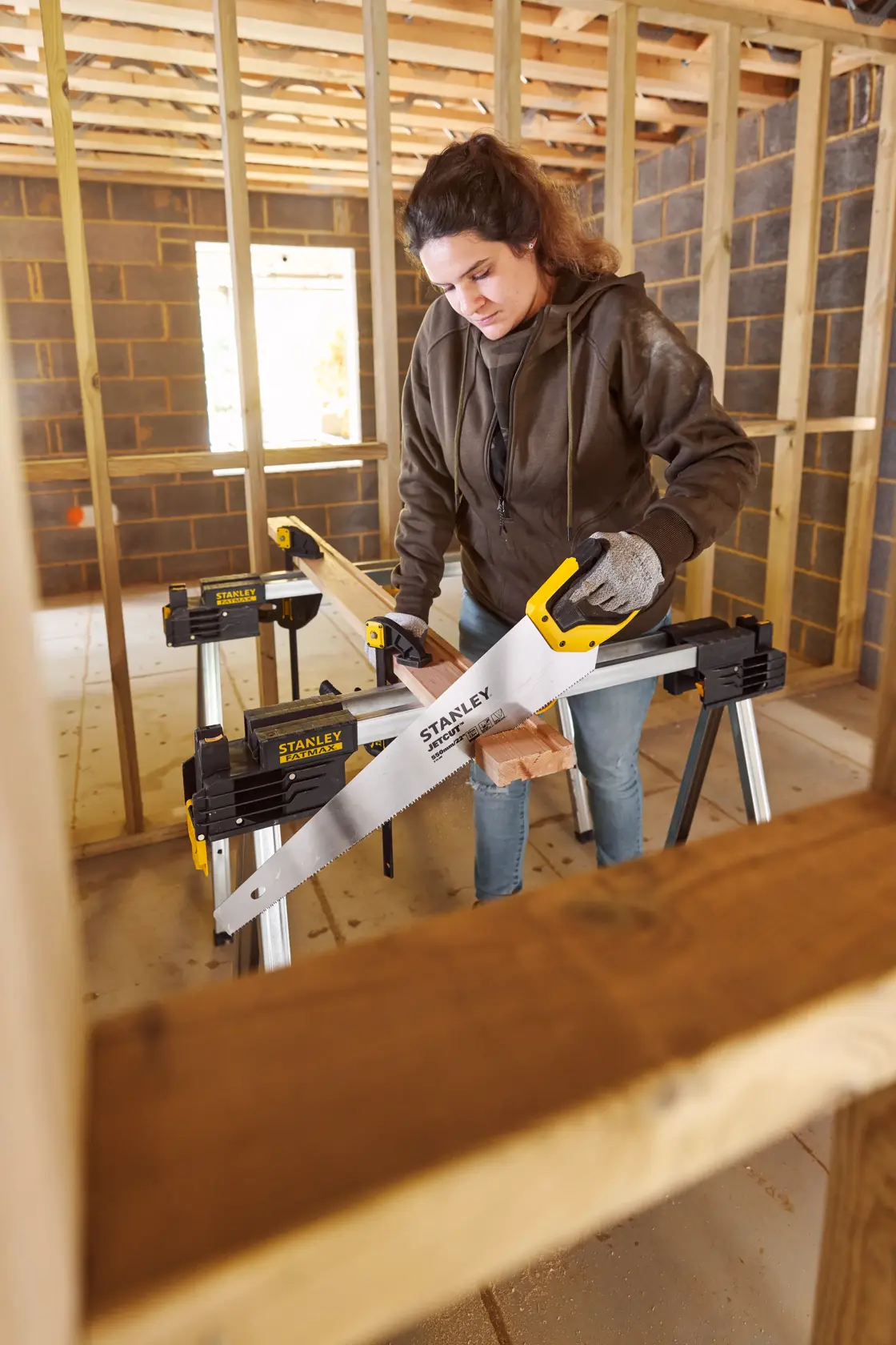 Photo of STANLEY 2-15-244 hand saw in use, cutting wood on sawhorse at construction site.