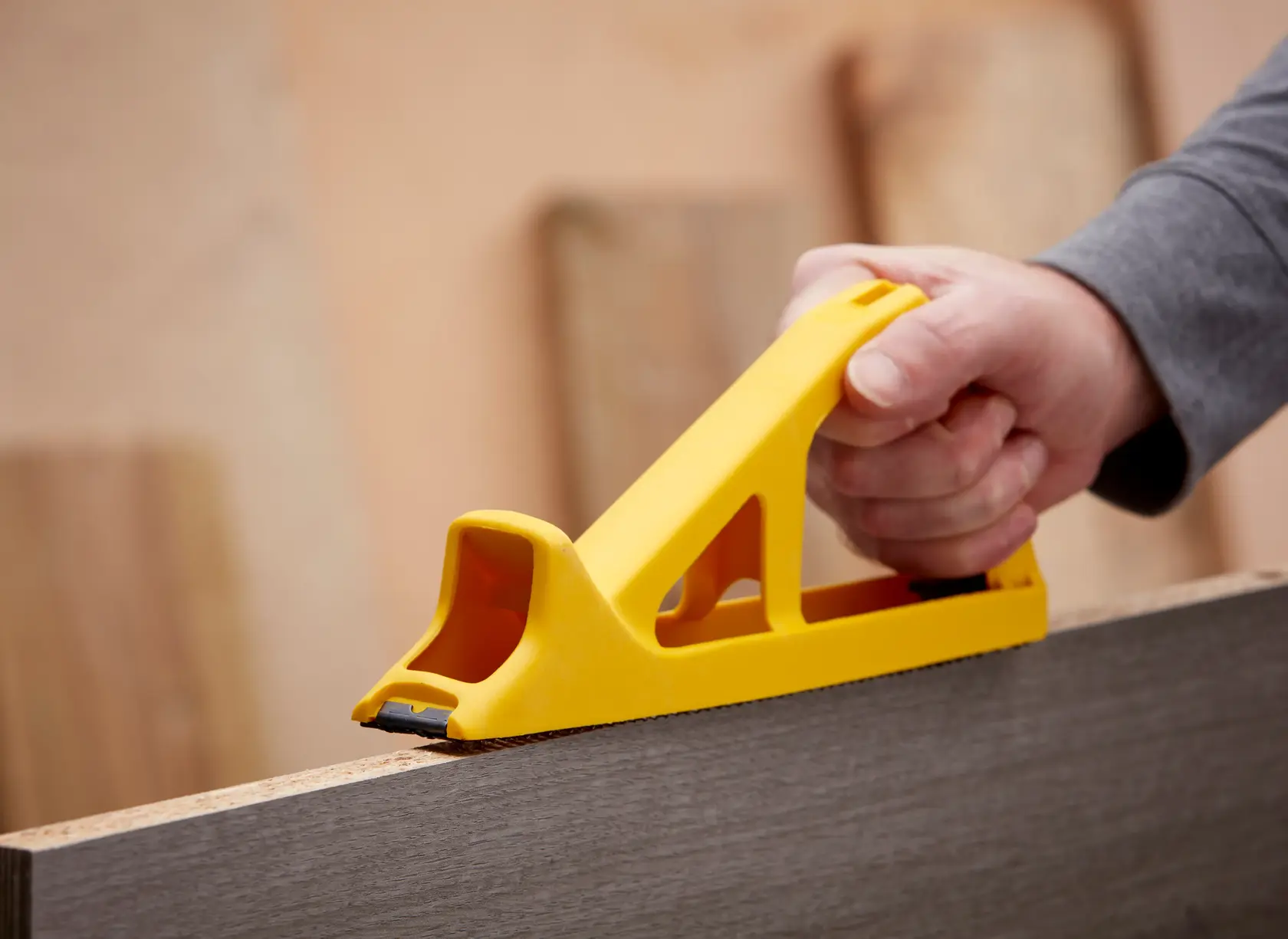 STANLEY 5-21-103 rasp plane in yellow, used for smoothing wood edges, shown in use from side angle.