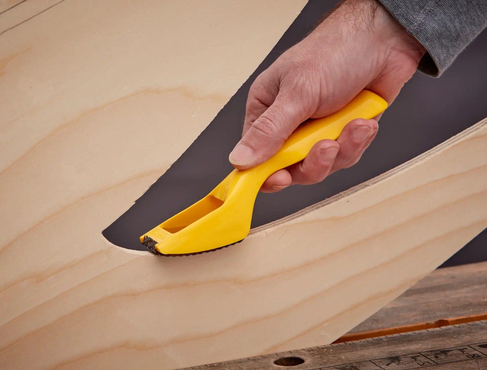 Photo of STANLEY 5-21-115 hand rasp tool with yellow handle smoothing wood edge.