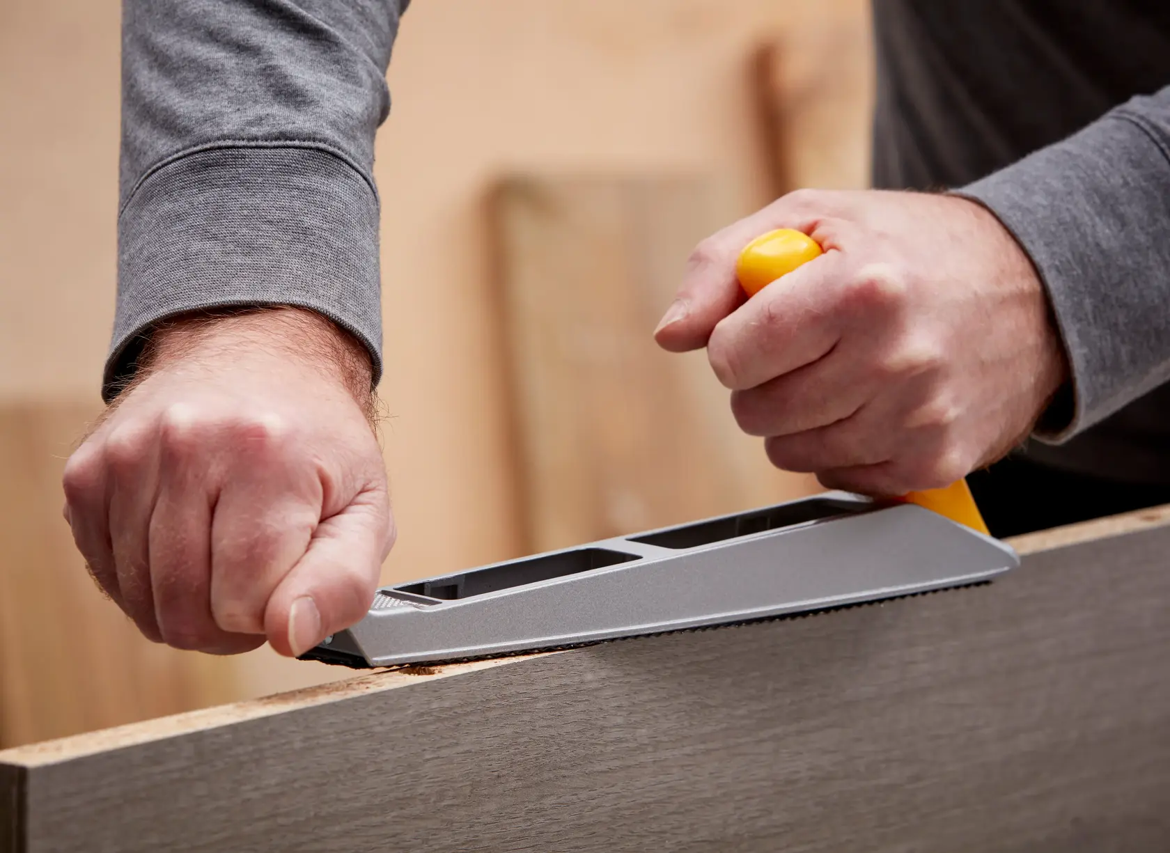Stanley 5-21-122 hand rasp tool with yellow handle in use smoothing wood surface, close-up photography.
