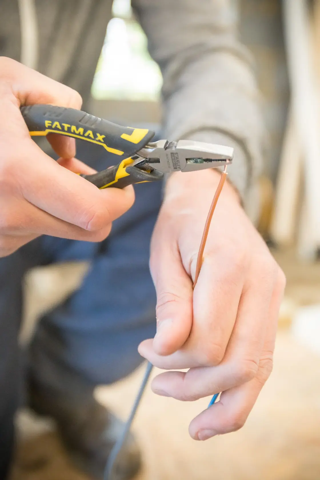 STANLEY FMHT0-80516 FATMAX pliers cutting wire, close-up photo, tool held by hand, photography category.