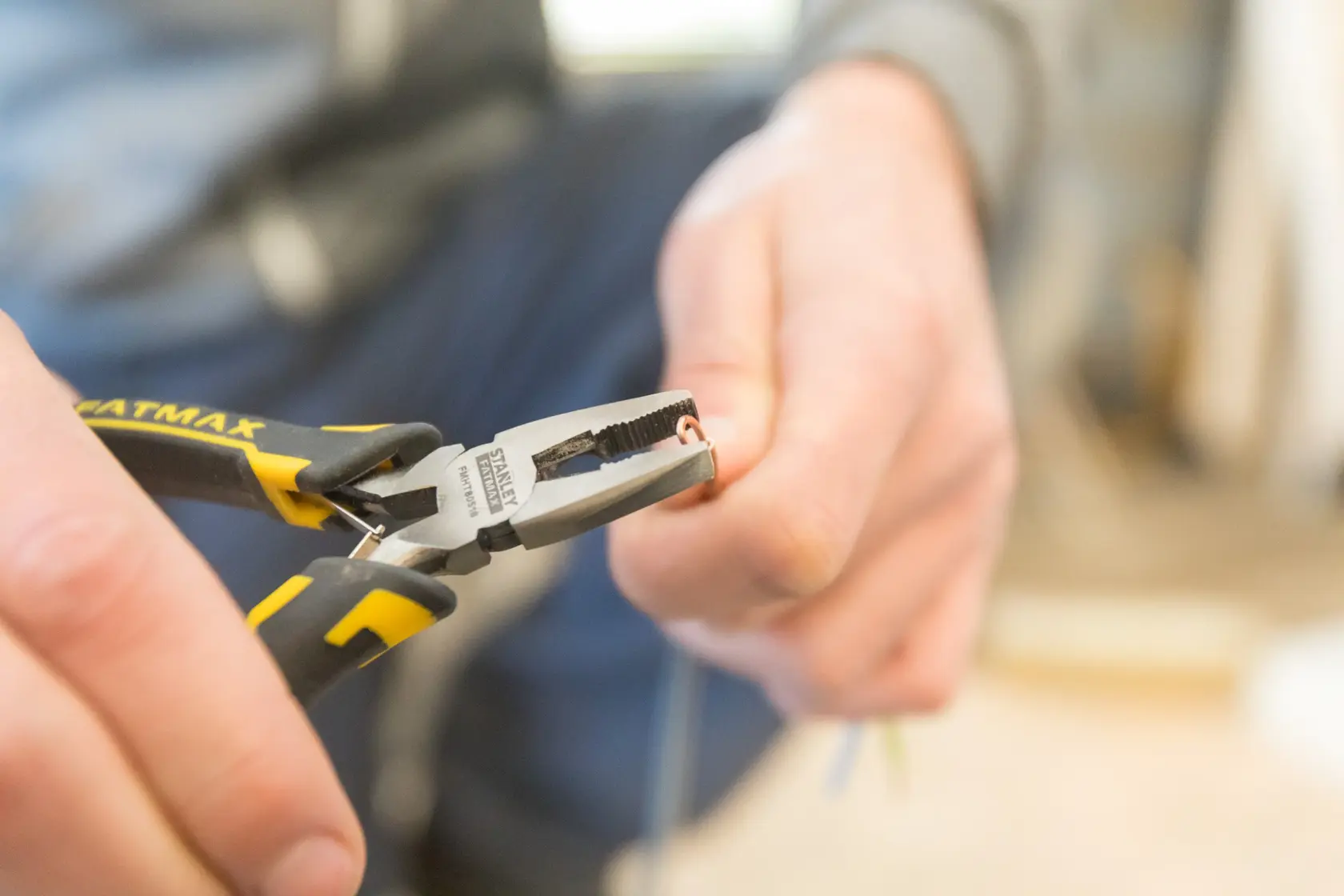Photo of STANLEY FMHT0-80516 pliers with black and yellow handles gripping a wire, close-up.