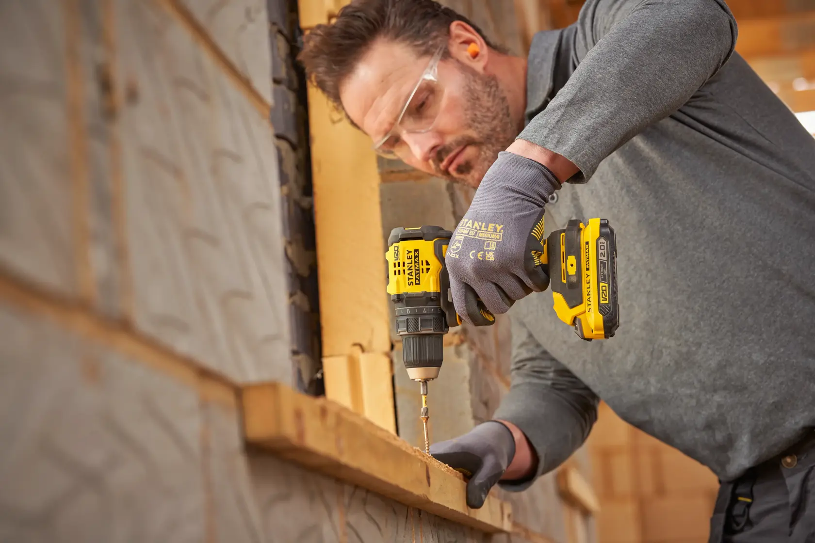 STANLEY SFMCD714D2T cordless drill driver in use on wooden construction, side view.