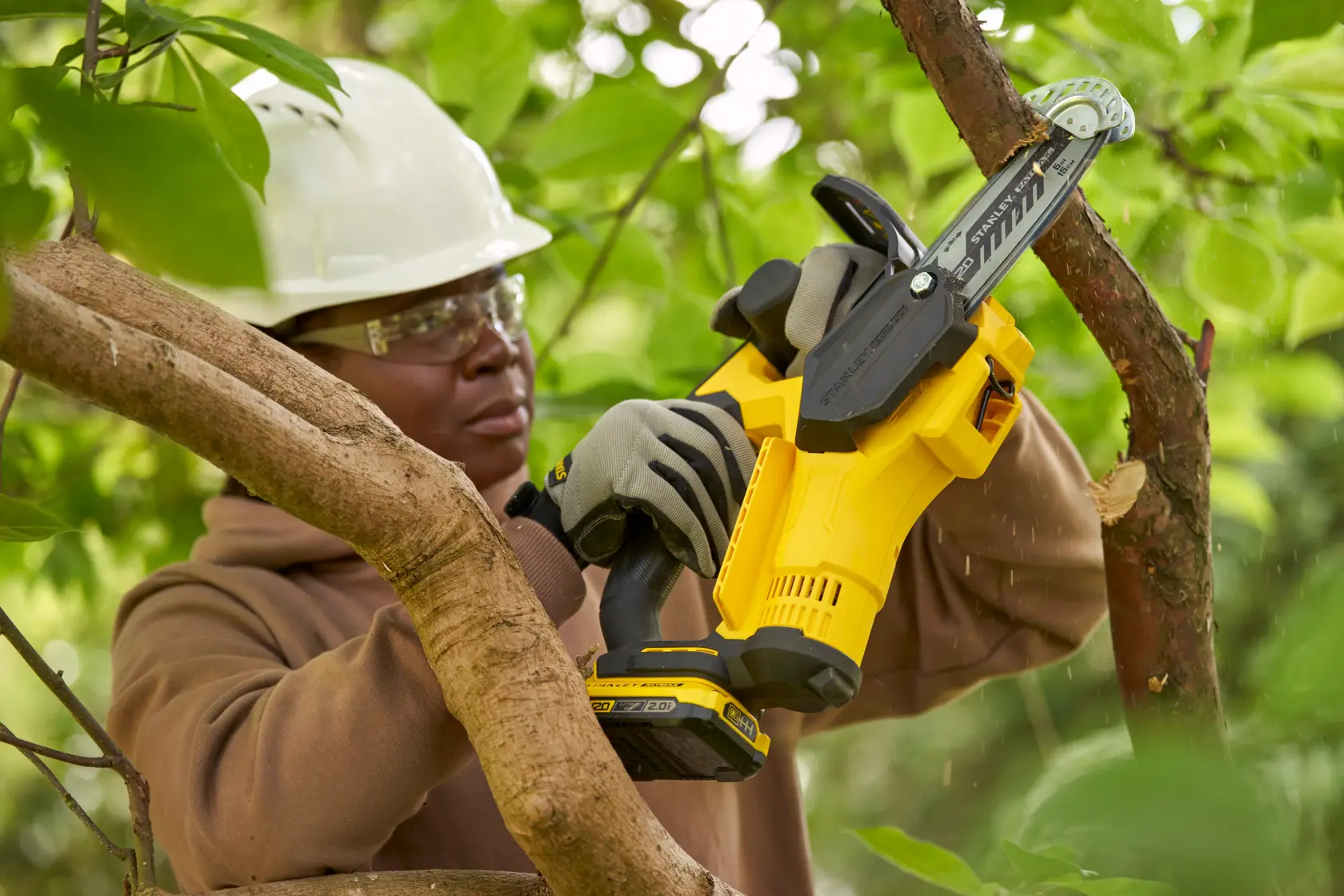 STANLEY SFMCPS415B cordless pruner used outdoors, trimming tree branches, close-up on tool in action.