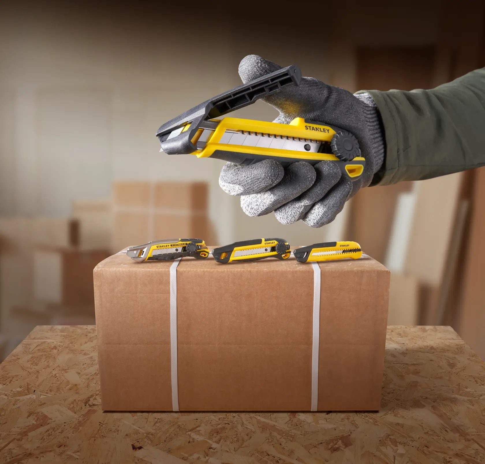 STANLEY STHT10500-0 yellow and black utility knife in use, opening cardboard box, seen from side angle.
