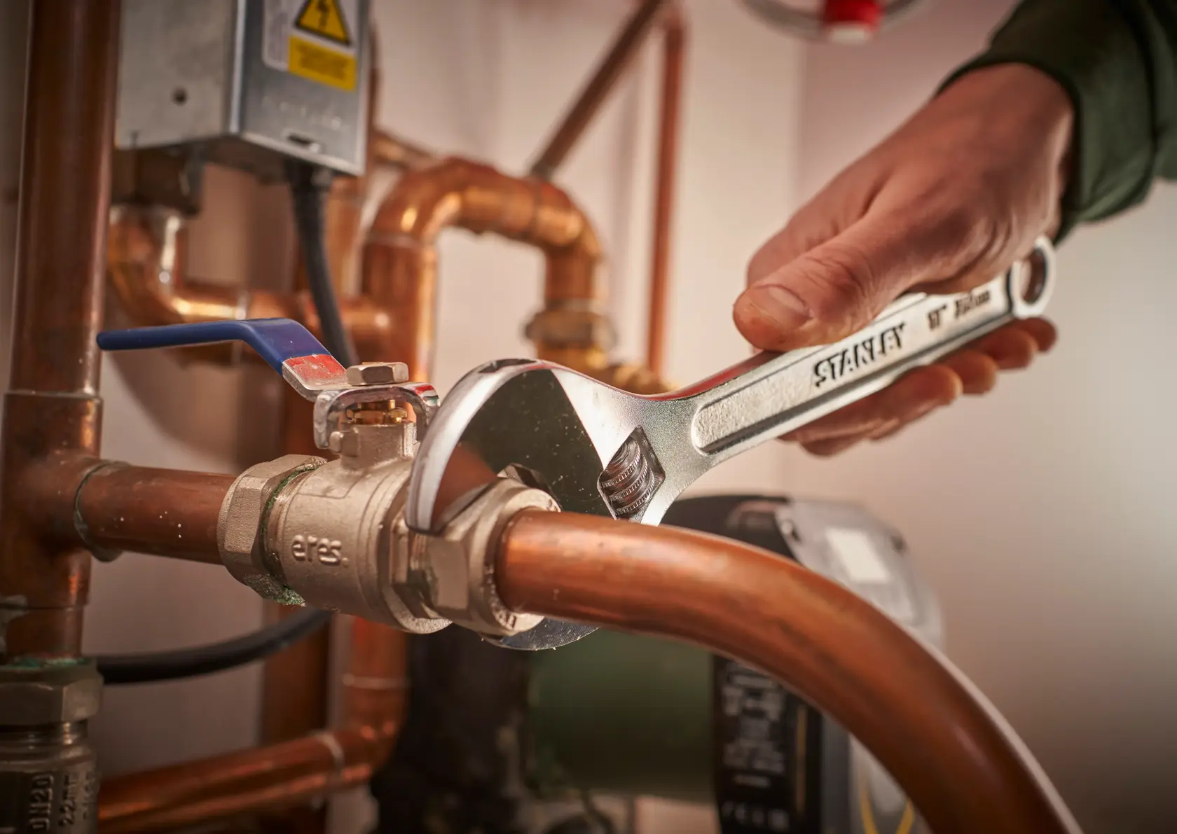 Photo of STANLEY STHT13123-0 adjustable wrench used on copper pipe fittings in a plumbing setting.