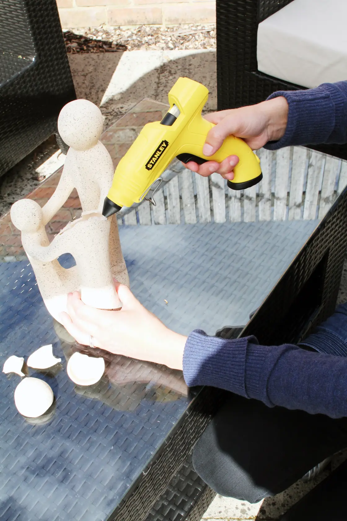 STANLEY STHT6-70416 photography of yellow glue gun used to repair stone sculpture on glass table.
