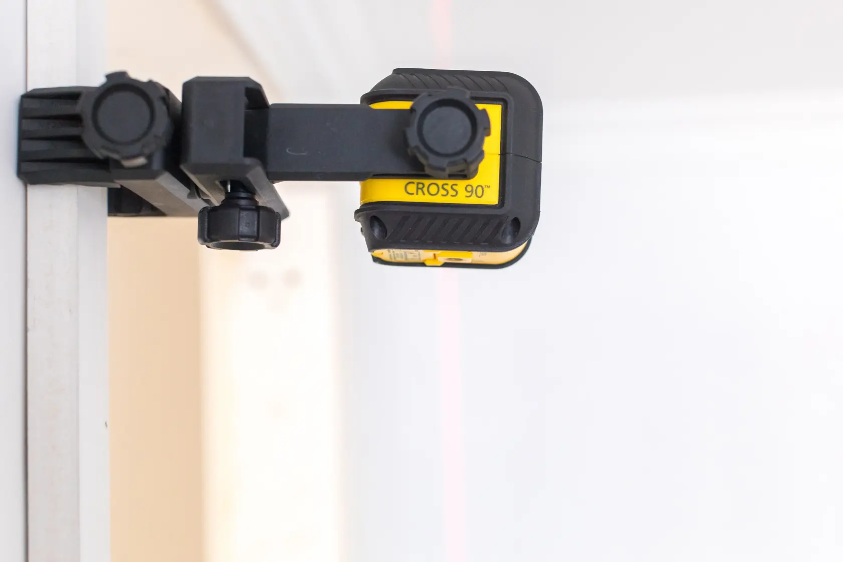 STANLEY STHT77592-1 cross line laser level mounted on wall, side angle, yellow and black body.