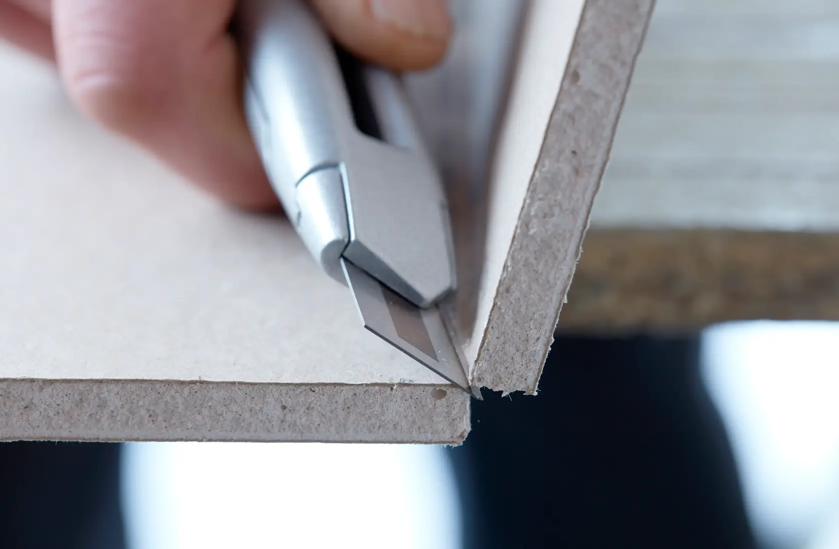 STANLEY STHT8-11818 utility knife cutting drywall, close-up side angle photography.
