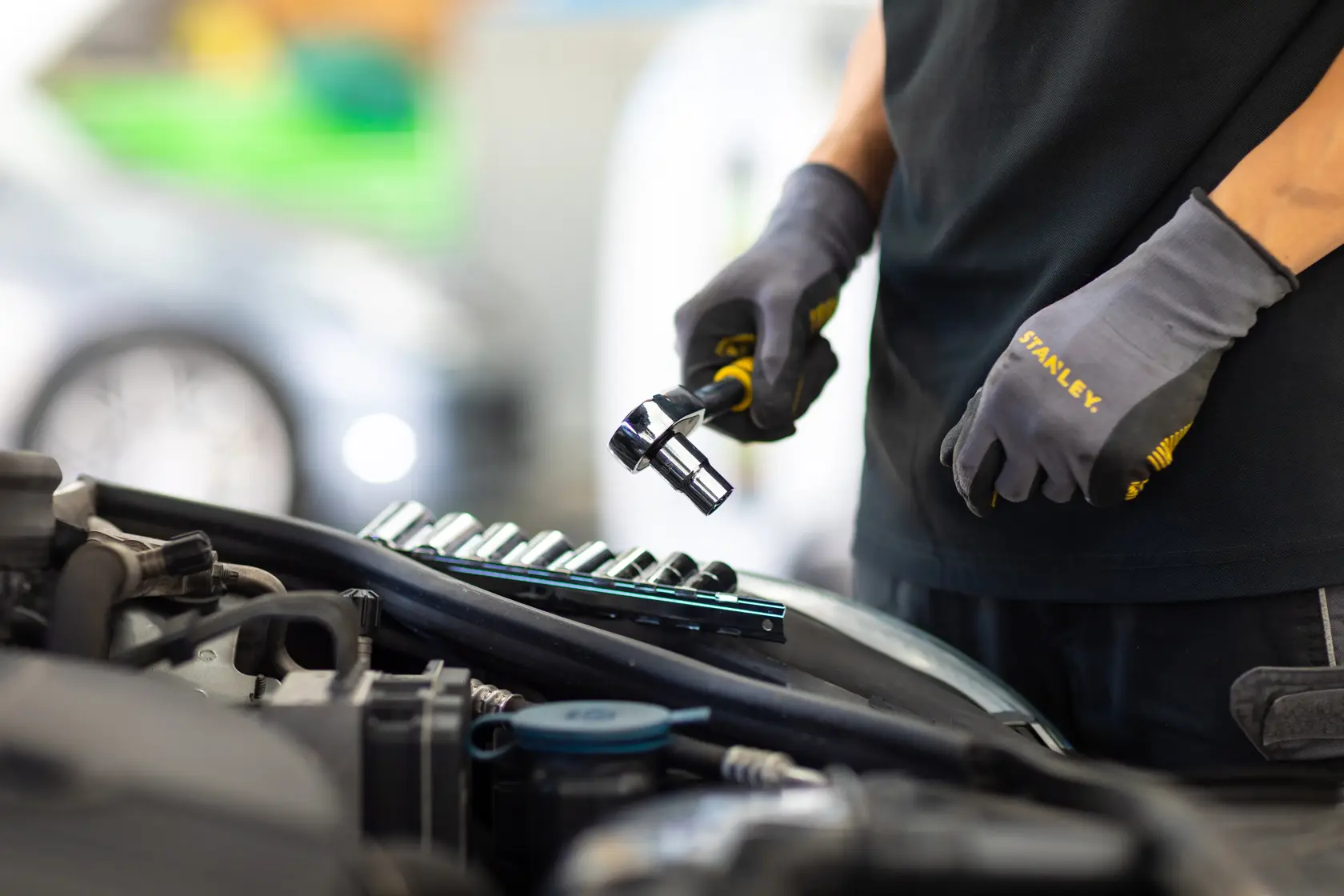 STANLEY STMT82670-0 ratchet set used for automotive repair, mechanic wearing STANLEY gloves.