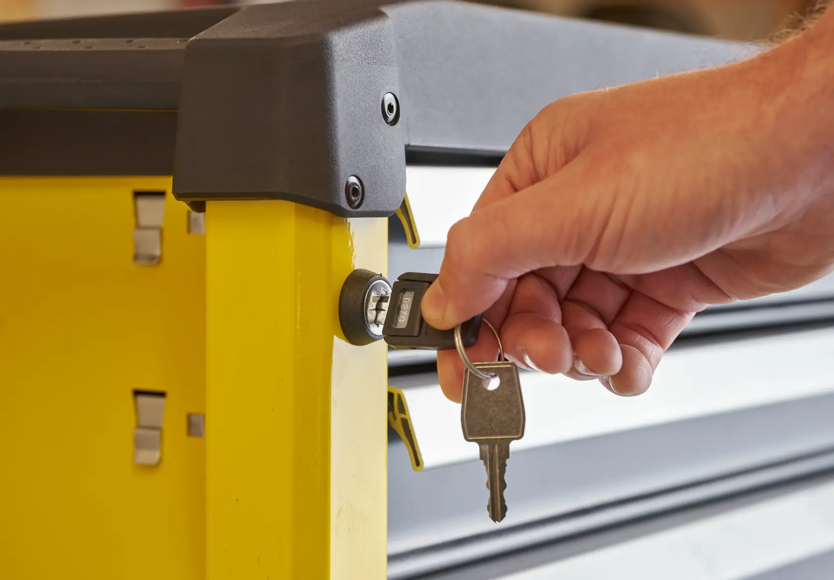STANLEY STST74306-1 tool storage cabinet side view with hand inserting key into lock.