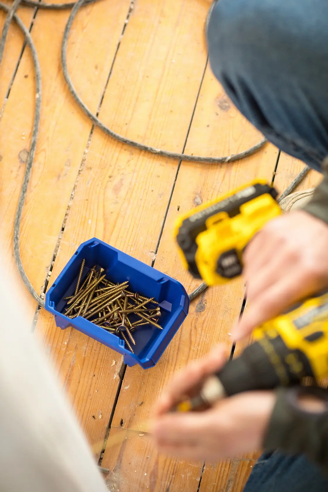 STANLEY STST82737-1 blue storage bin with screws on wooden floor, photographed from above.