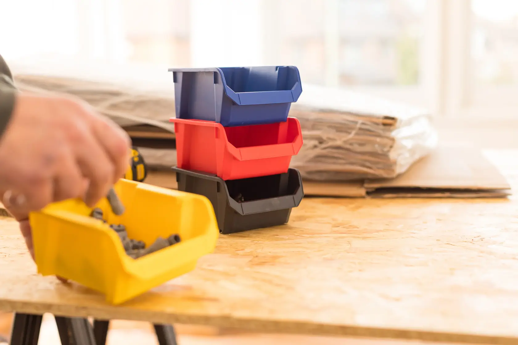 STANLEY STST82737-1 stackable plastic storage bins in blue, red, black, and yellow on a workshop table.