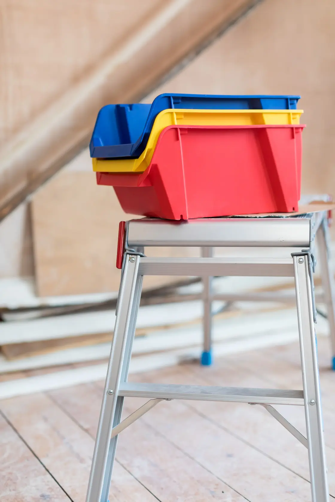 STANLEY STST82742-1 stackable plastic storage bins in red, yellow, and blue on metal workbench.