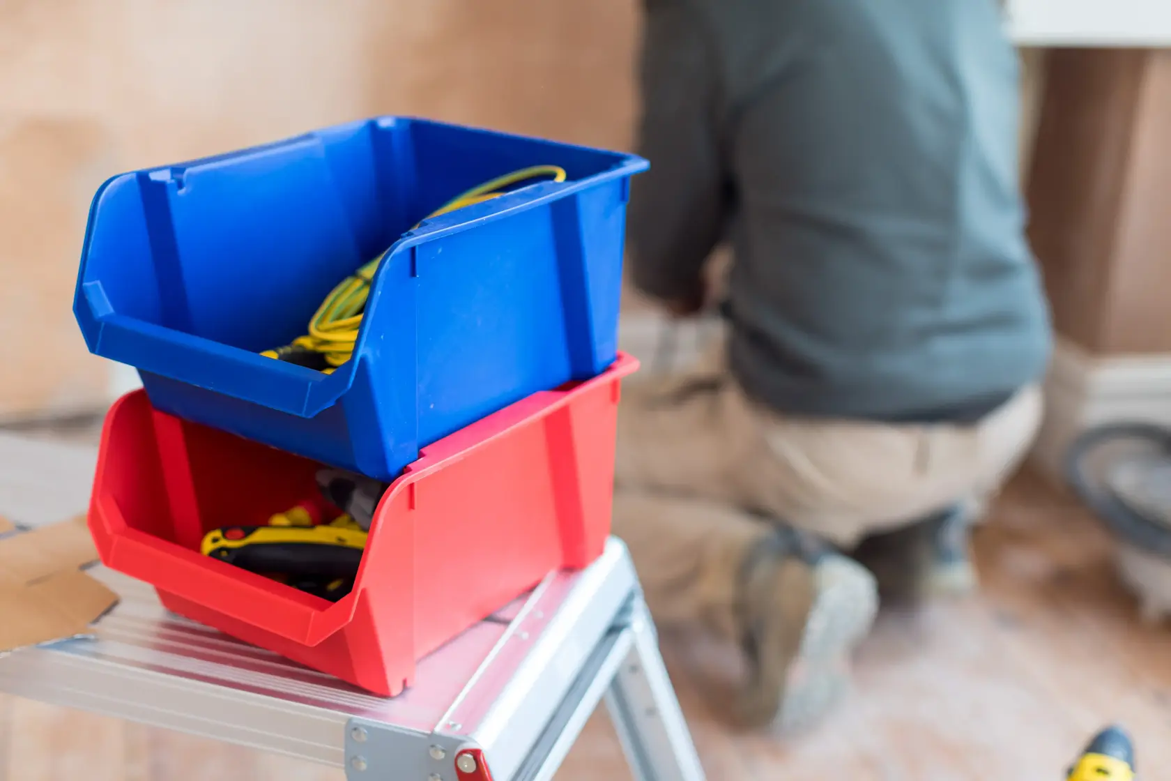 STANLEY STST82743-1 photography of red and blue storage bins on a step ladder, filled with tools and cables.