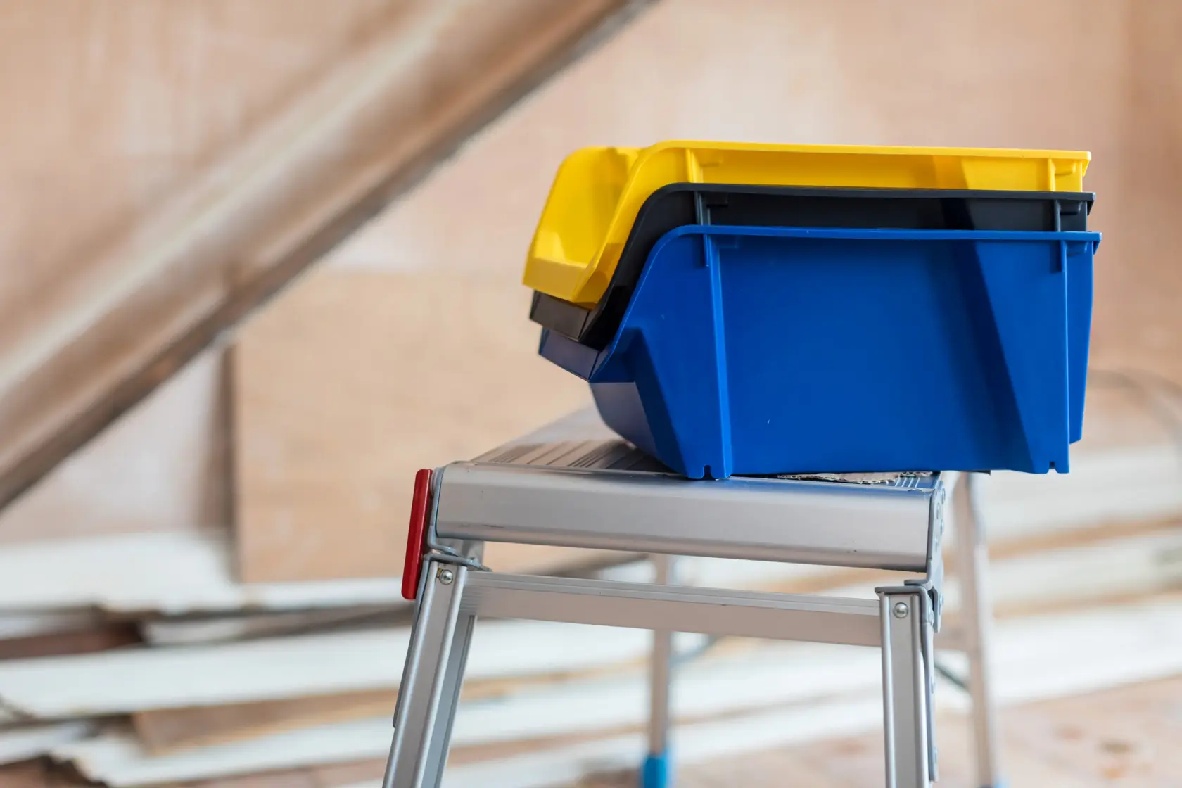 STANLEY STST82743-1 stackable yellow and blue storage bins on a metal step ladder side view.