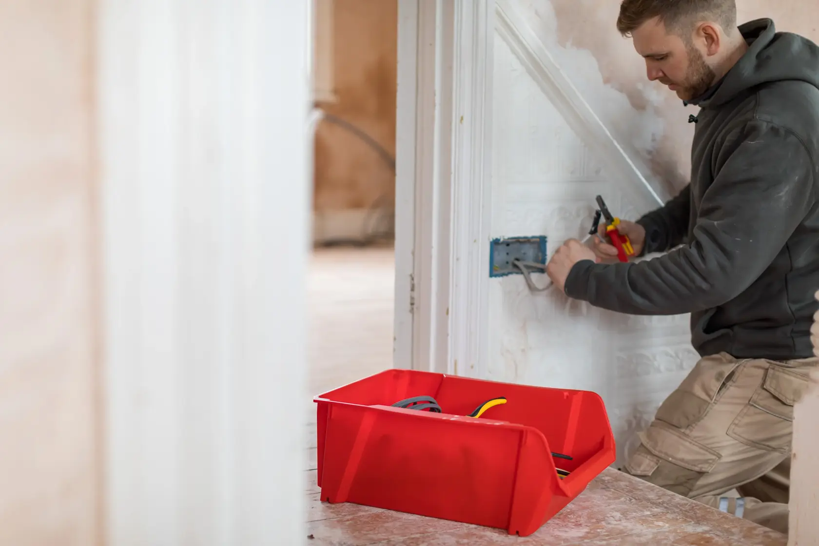 STANLEY STST82745-1 red storage bin for tools and cables in use during electrical work, side angle.