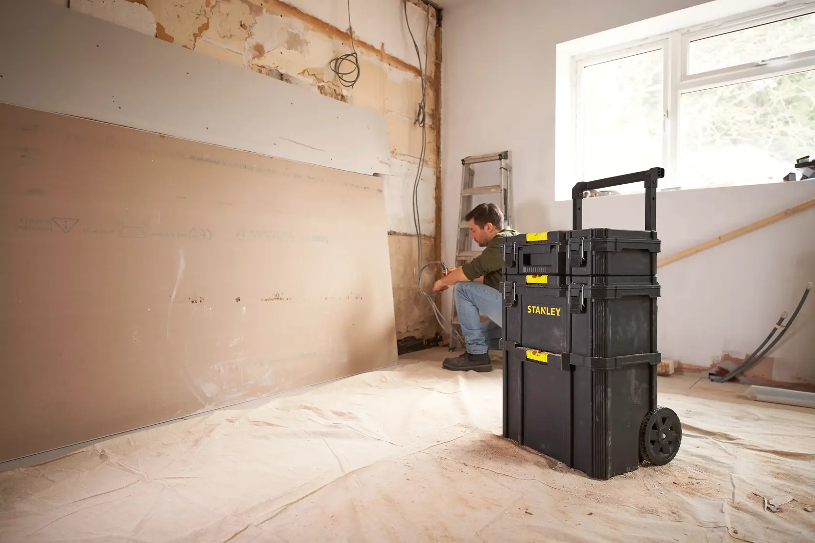 STANLEY STST83319-1 rolling tool chest in a remodel room, black plastic with yellow accents.